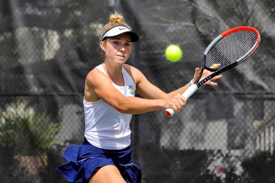 A women’s tennis player returns a serve.