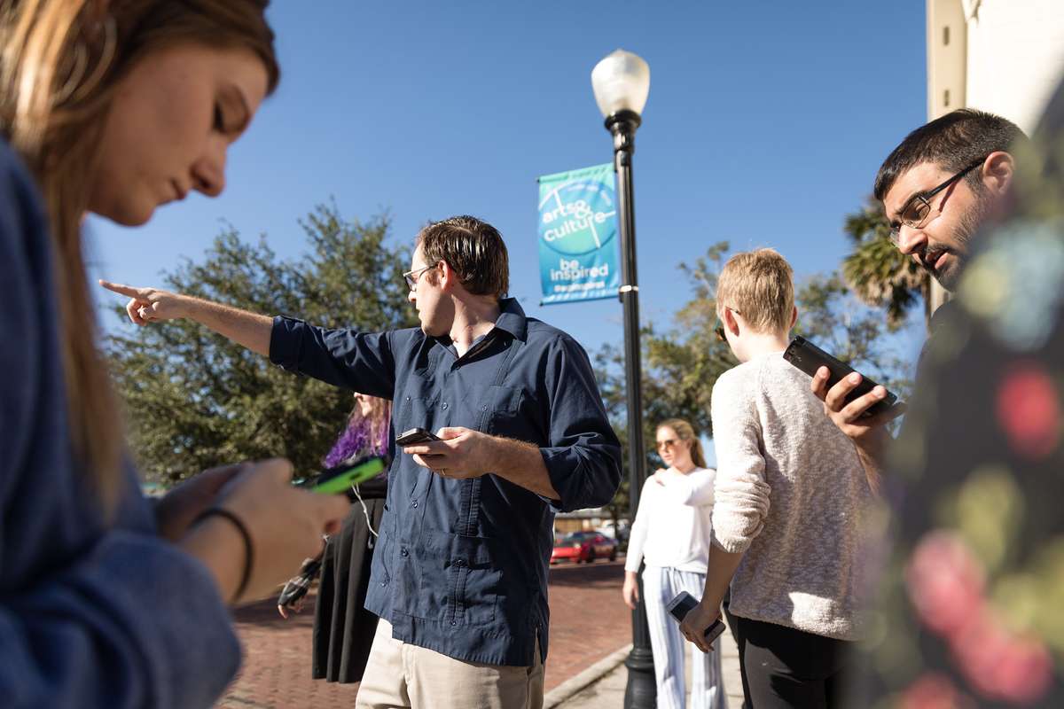 Professor Dan Myers pointing to something offscreen while students are looking at their smartphones.