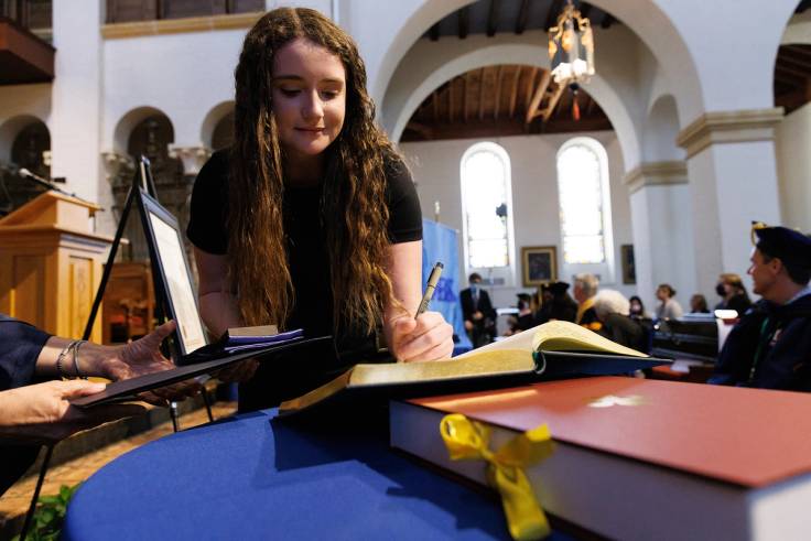 A student signs a book after being inducted into Phi Beta Kappa honor society.