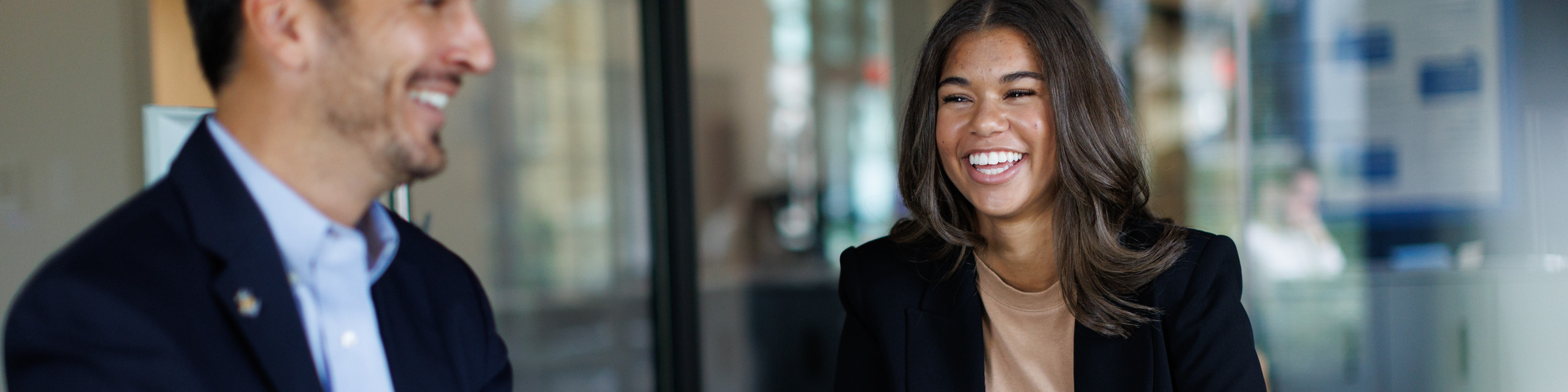 Kaley Klatt smiling and sitting with laptop in office with man in suit.
