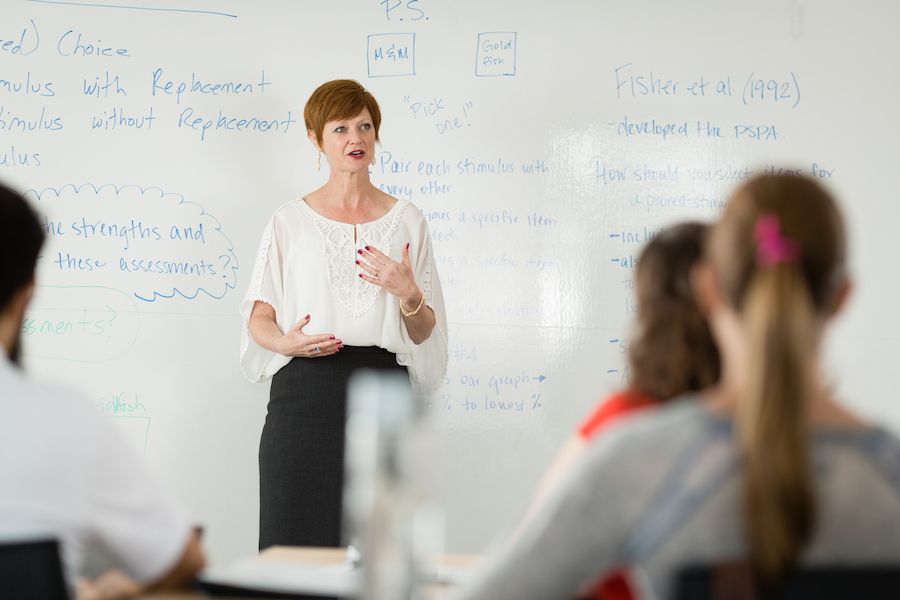 Woman professor speaking to a graduate class at 鶹ƵAPP College.