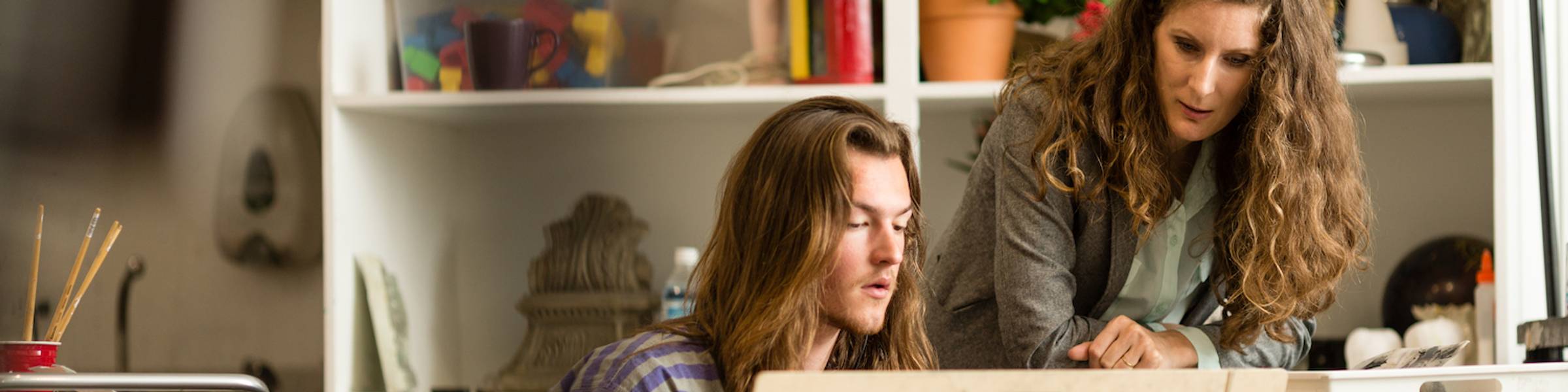 A Rollins College professor talks with a student in a painting class.