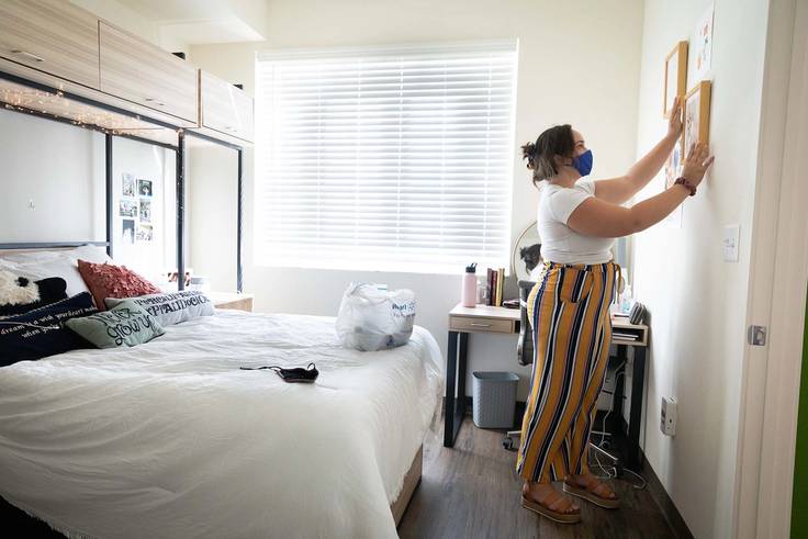 A student hangs up a picture in their Lakeside dorm room