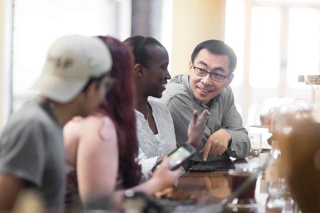 An economy college professor is talking with his students at a local cafe.