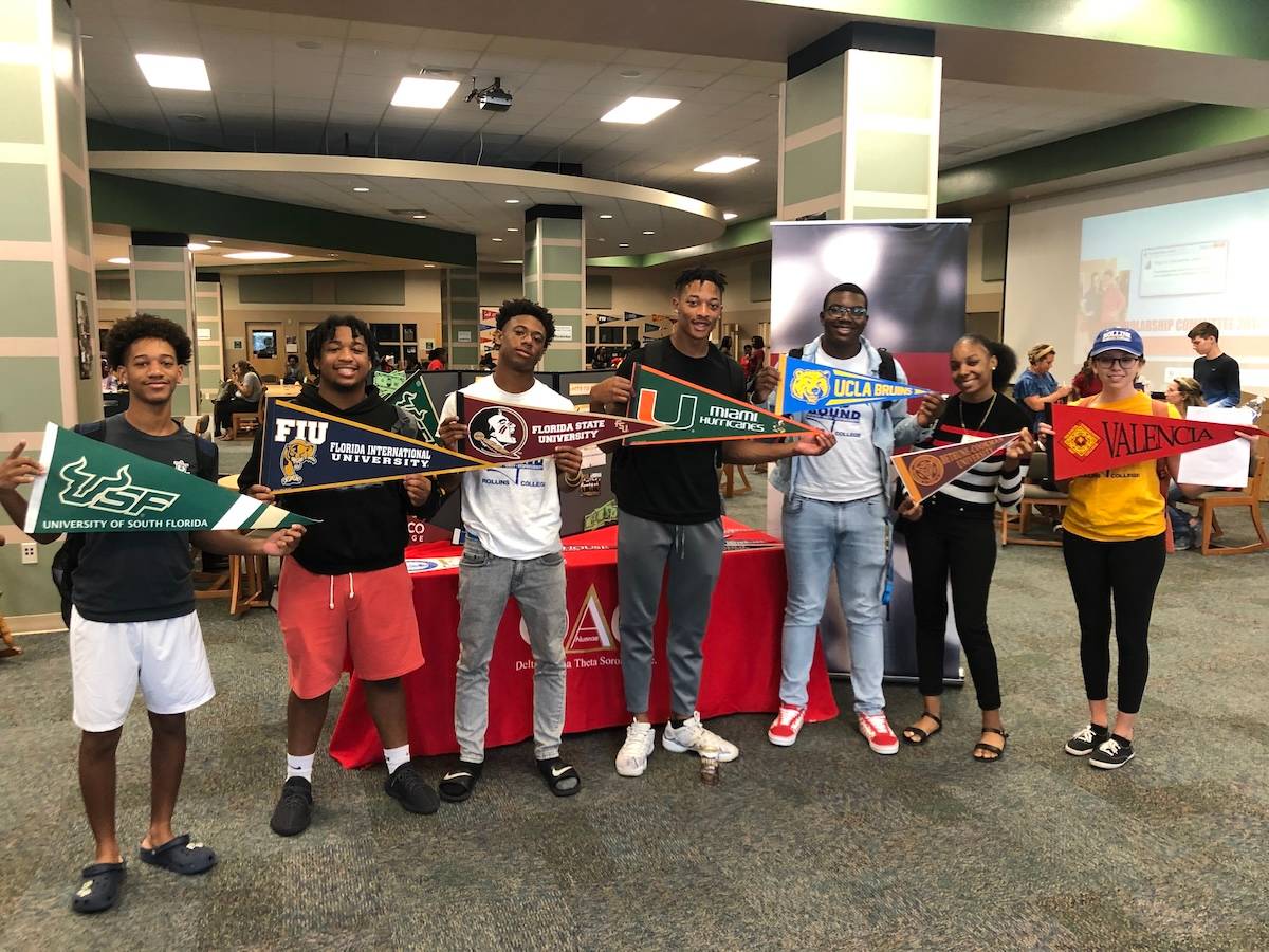 Upward Bound students holding college banners.