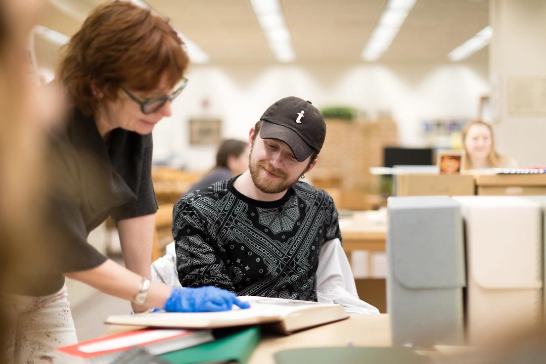 Professor Claire Strom pointing out something interesting in a book to a college student for a research project.