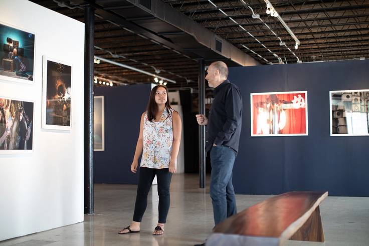 A student intern and an art gallery owner discuss an artwork.