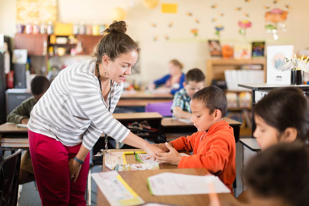 An elementary education teacher works one on one with a student.