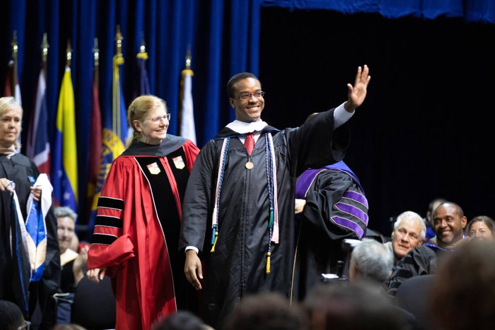 A graduating student waves at the audience.