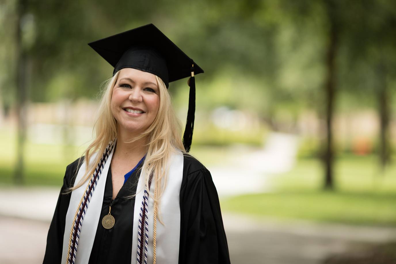 Shannon Burrows outside on campus wearing a cap and gown for commencement.