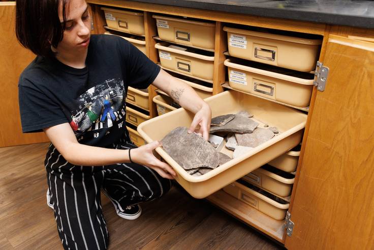 A Rollins student examines a shell artifact. 