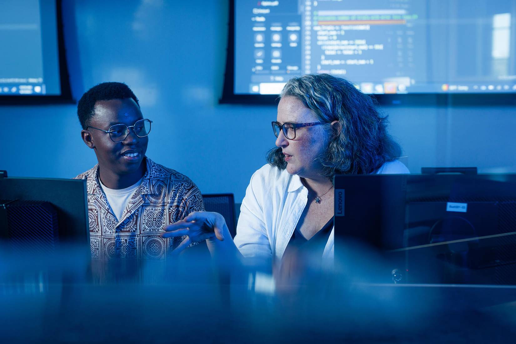 A computer science student and faculty member work together on collaborative research in a computer lab.