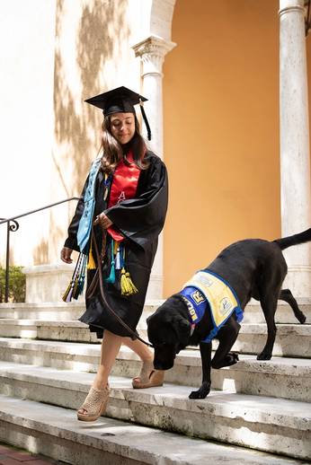 Marissa Cobuzio ’19 walks her service dog, Ari, down stairs on the Rollins campus.