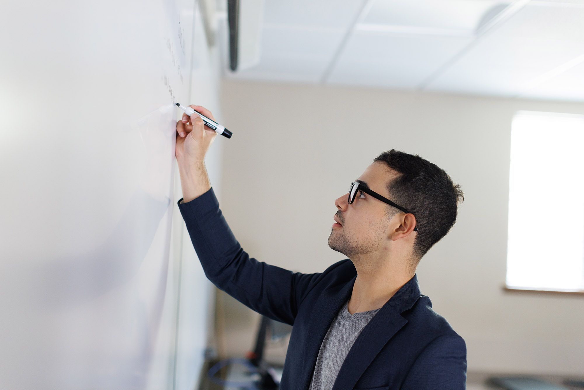 Professional writing notes on a whiteboard during a presentation or meeting.