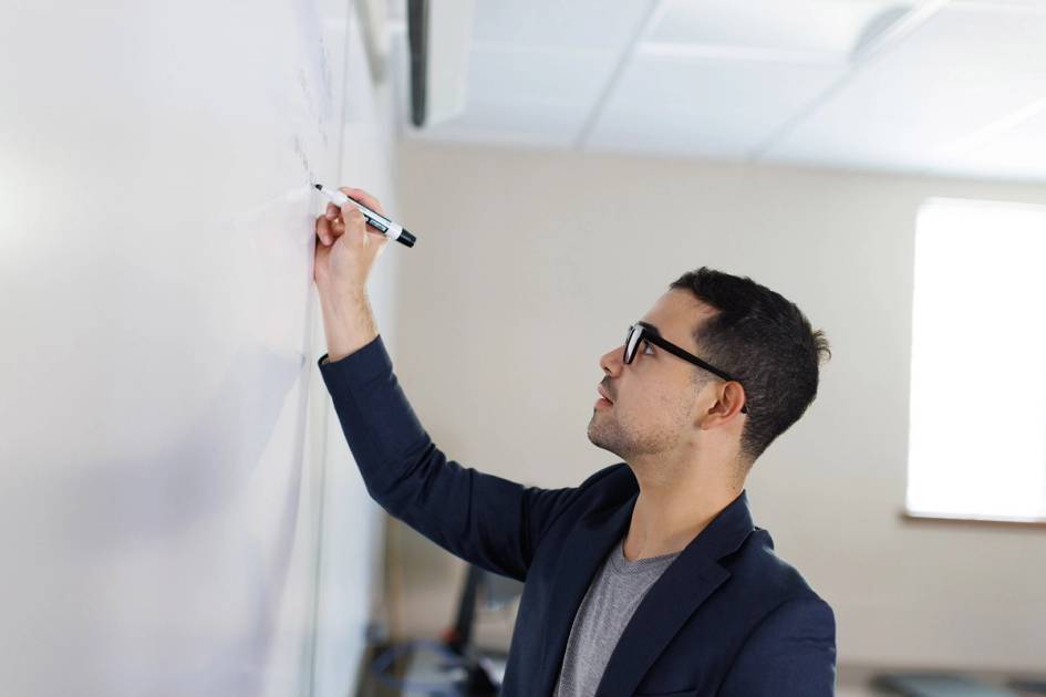 Professional writing notes on a whiteboard during a presentation or meeting.