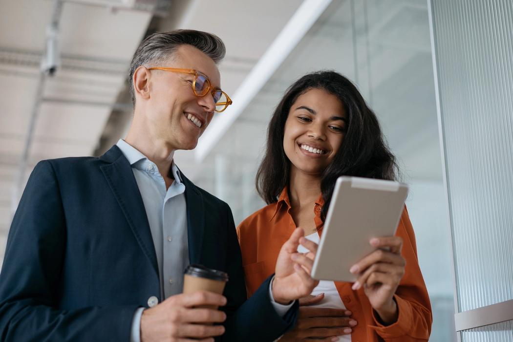 Two communication professionals discuss a campaign on a tablet.