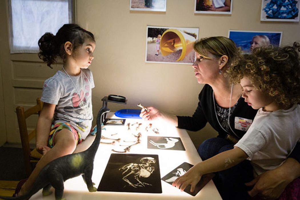 Teacher works with two children at a light table.