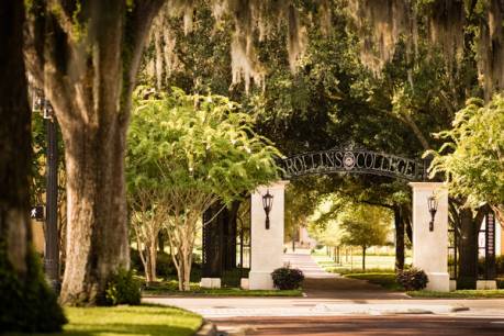 An entryway sign at Rollins College surrounded by oak trees. 