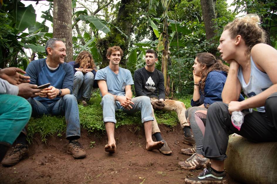 A professor sits with a group of students during a field study in Tanzania.