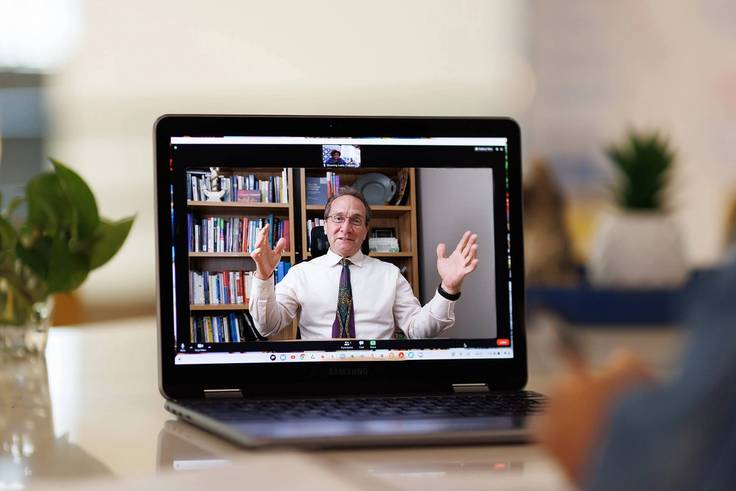 A college professor meets one on one with a student via video conference.