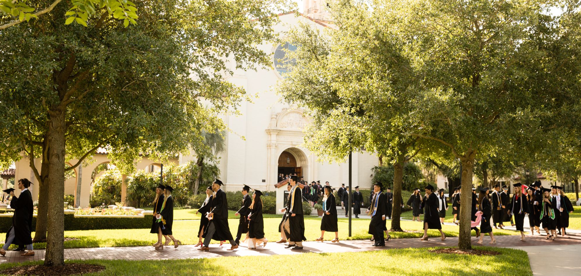 Students walking in caps and gowns to their commencement.