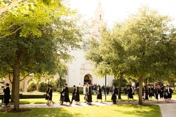Rollins students walk past the rose garden during commencement.