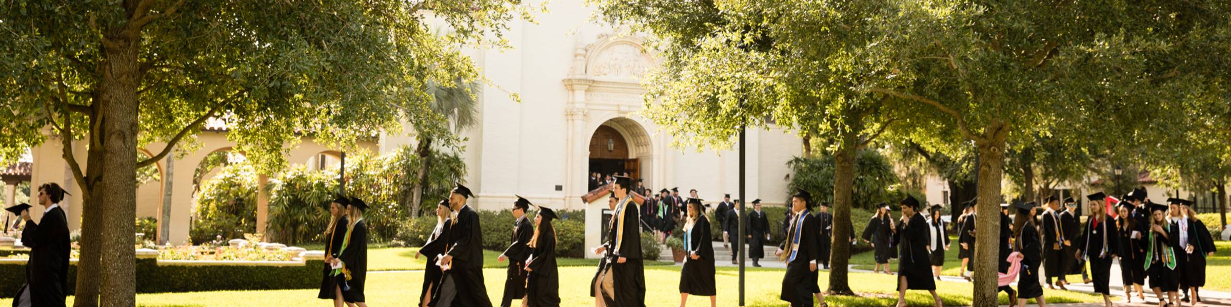 Students walking in caps and gowns to their commencement.