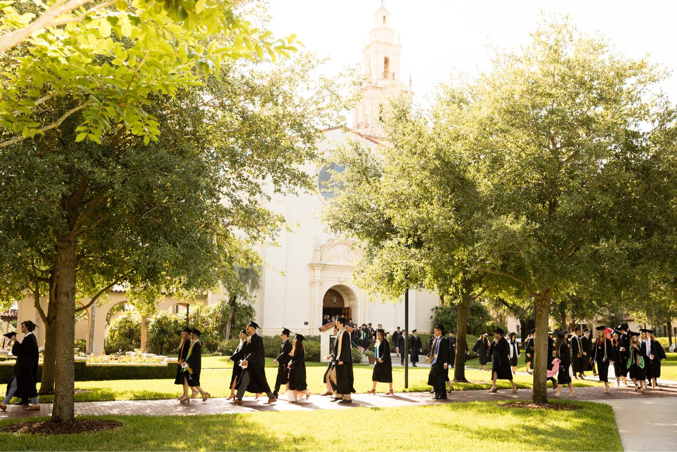 Rollins students walk past the rose garden during commencement.