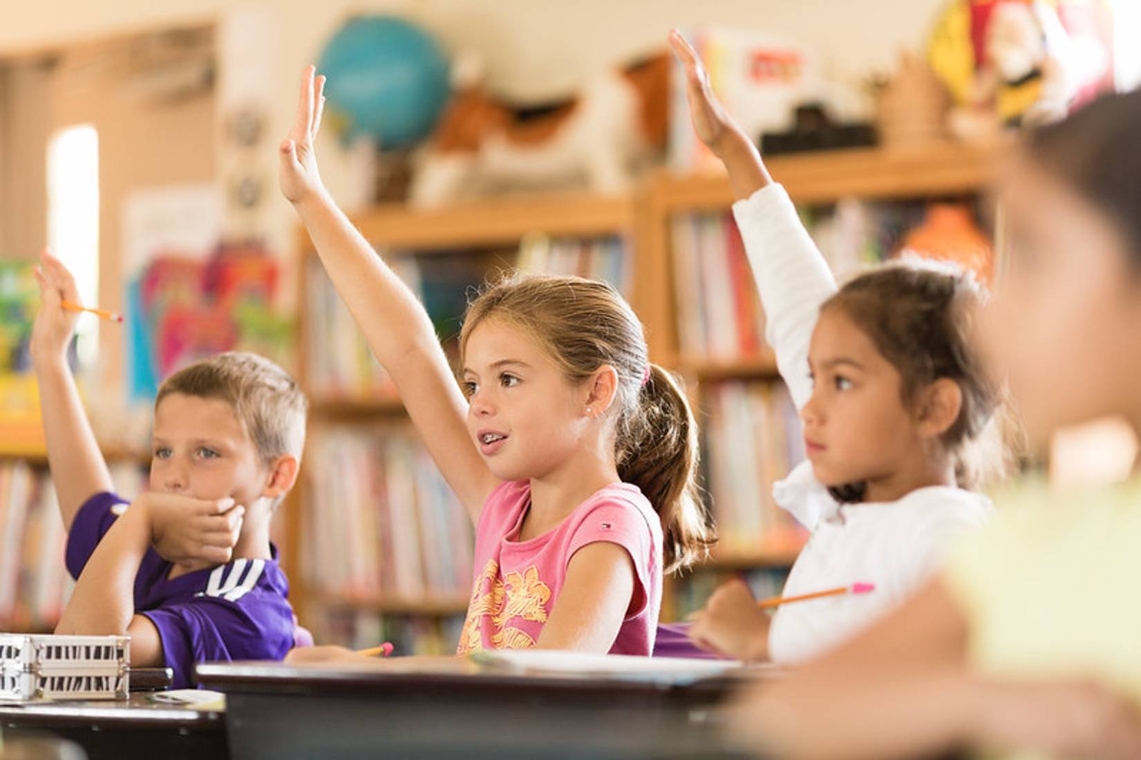 Photo of kids raising hands at school