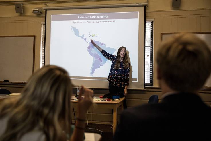 A Latin American & Caribbean professor speaks to a class while pointing at a map of the region.