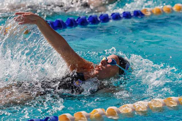 A swimmer in the pool during a meet doing the backstroke.