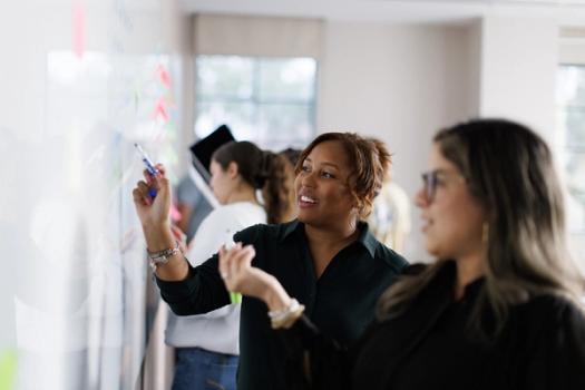 A student works through a problem with a professor at the whiteboard.