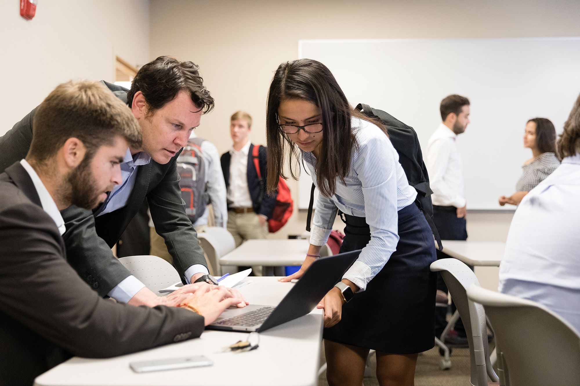 A professor helps two students with a presentation.