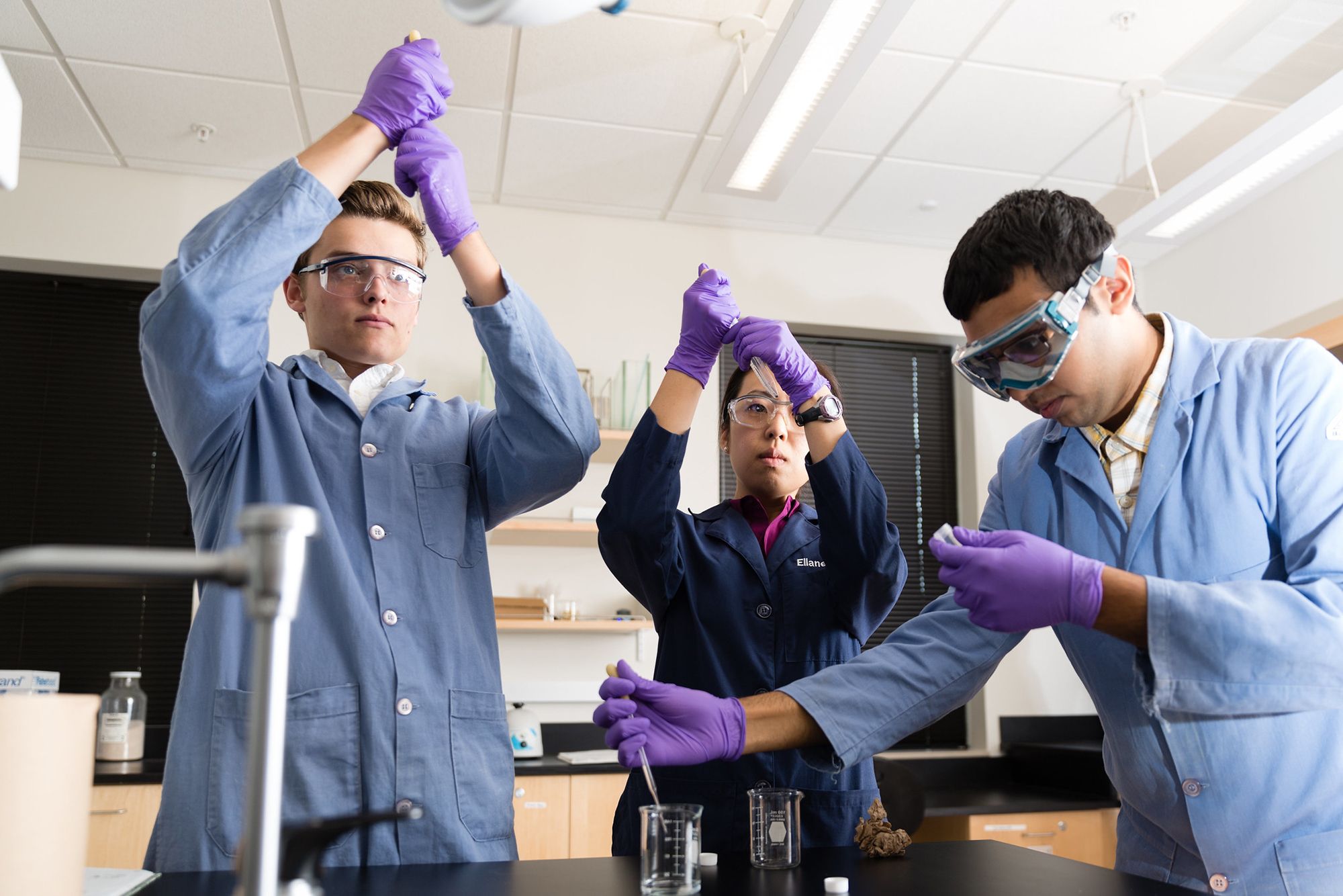 A professor and two students conduct chemistry research.