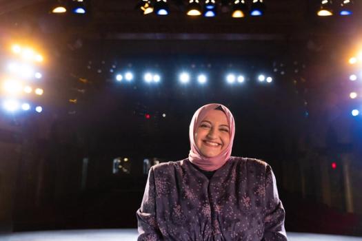 Student smiles at camera on The Annie Russell Theatre stage at Rollins College.