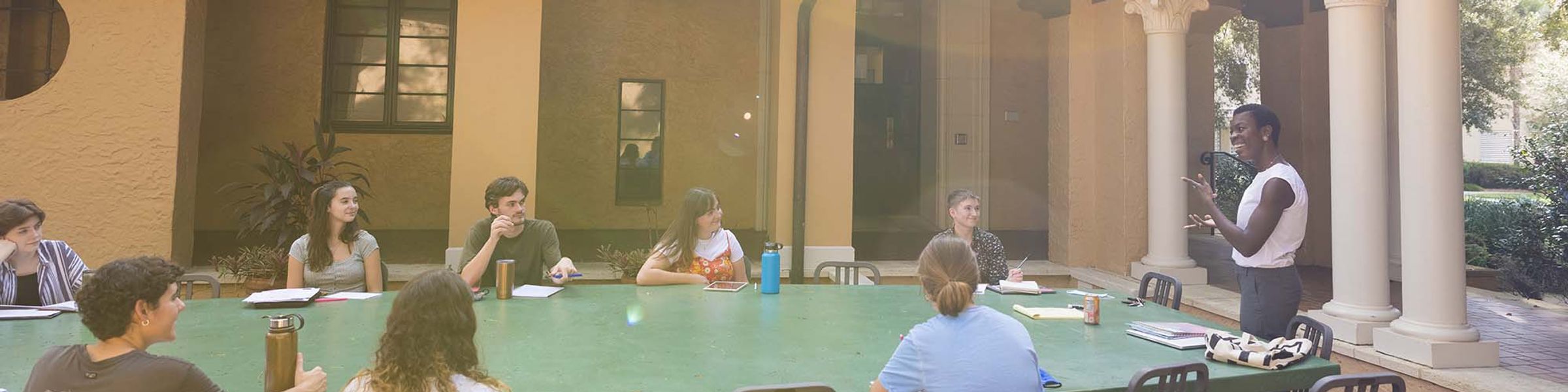 Students and a professor have a discussion at an outdoor classroom on Rollins campus.