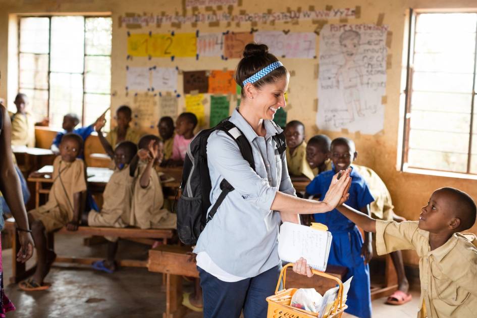 A graduate education student high fives a Rwandan student on an international field study.