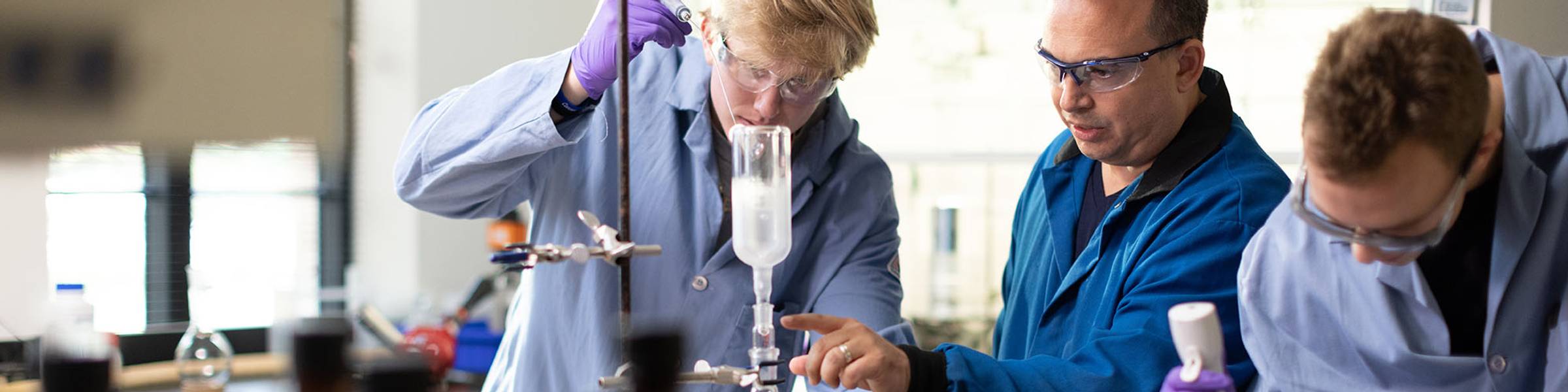 Two students conduct chemistry research with their professor.