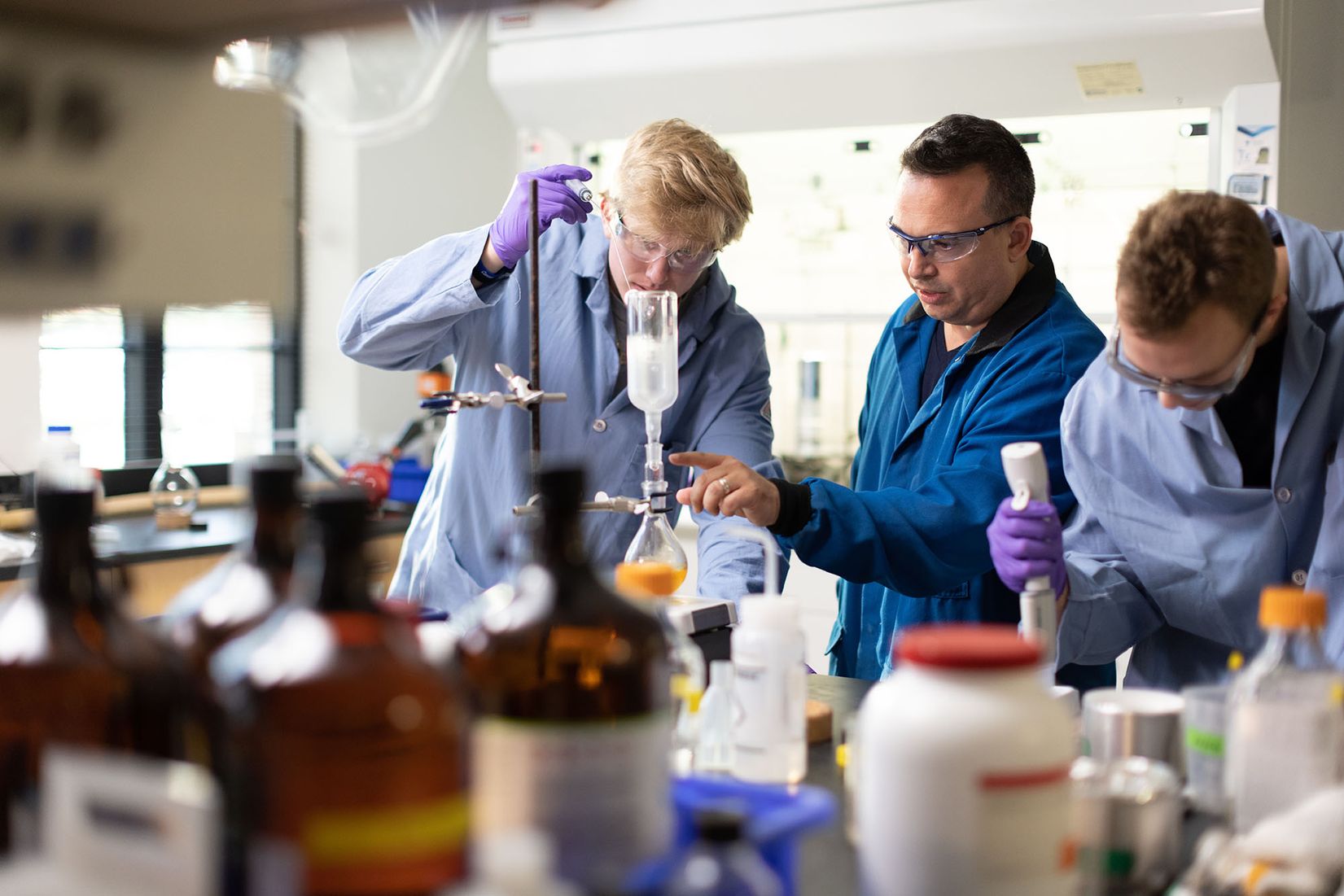 Chemistry students work with a professor in a lab.