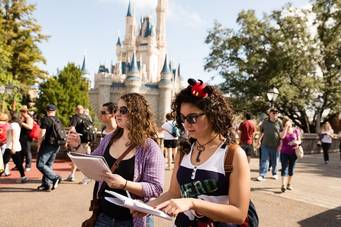 Students walk around Disney World, in front of the castle.