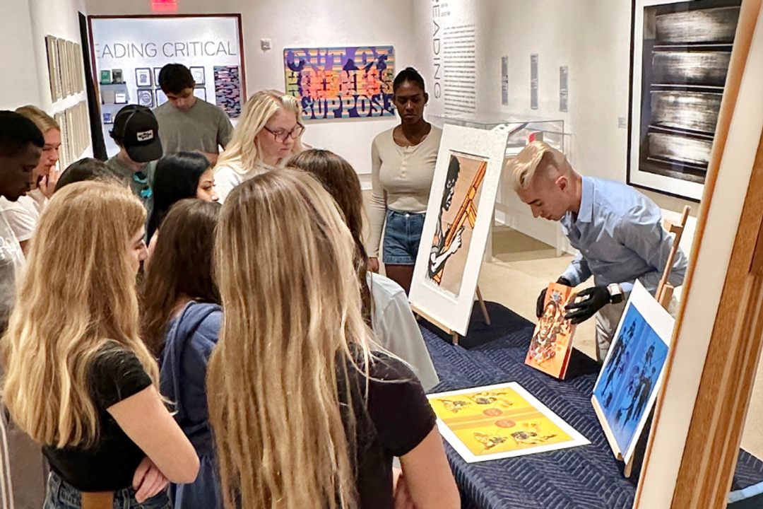 Children gather around an artwork of a bearded man's face