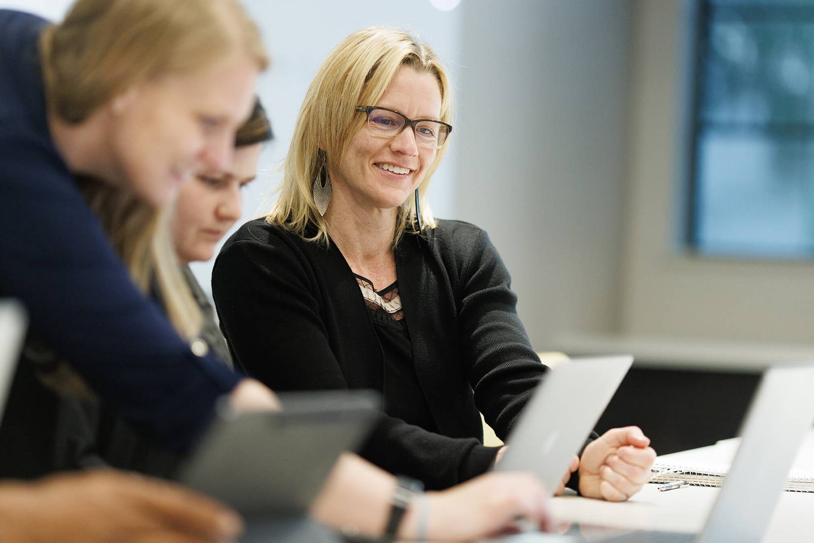 A student smiles as a professor explains a concept to a small group of students.