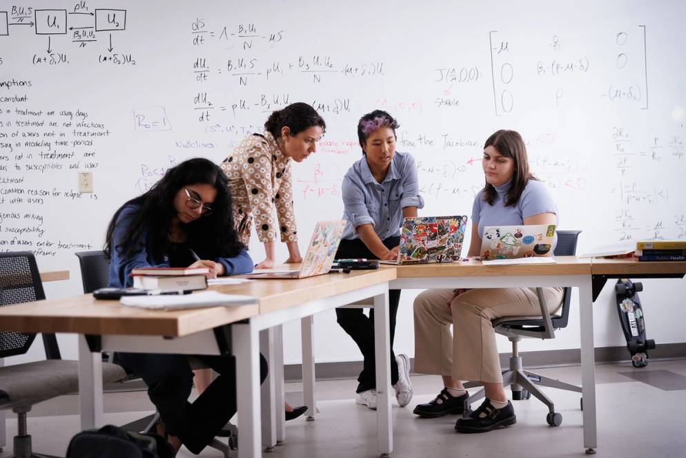 Math students and professor collaborate on a project.