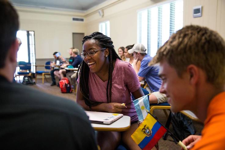 A group of three Rollins students hold Latin American country flags as they learn about their cultures.