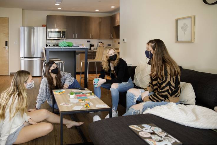 Four female students socializing in the living room of their dorm at Lakeside.