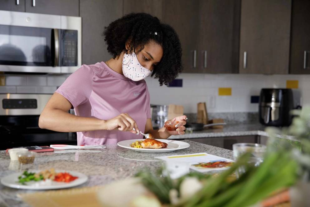 A student cooks a meal in her Lakeside dorm using a meal kit from Dining Services. 