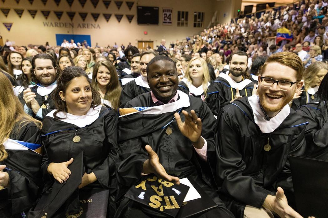 Students in their gowns clap at the commencement ceremony