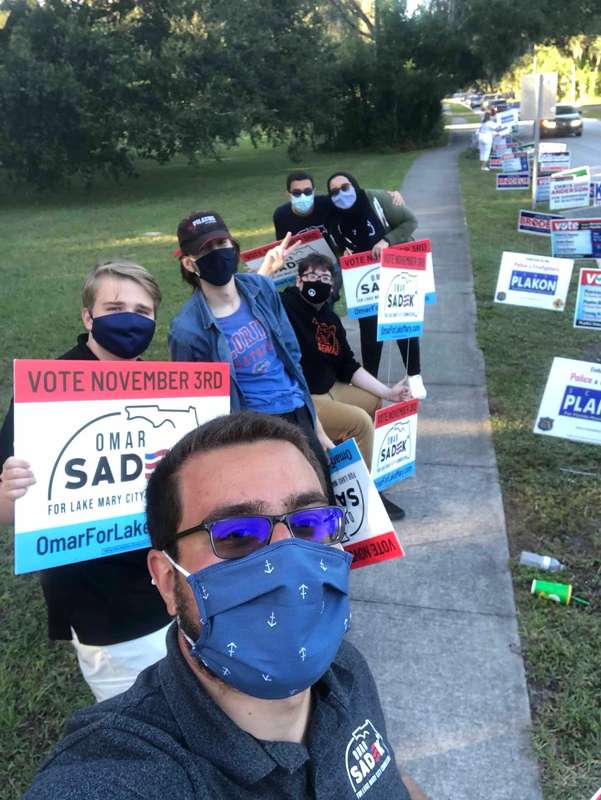 Supporters of Omar Sadek ’19 hold signs promoting his run for city commission.