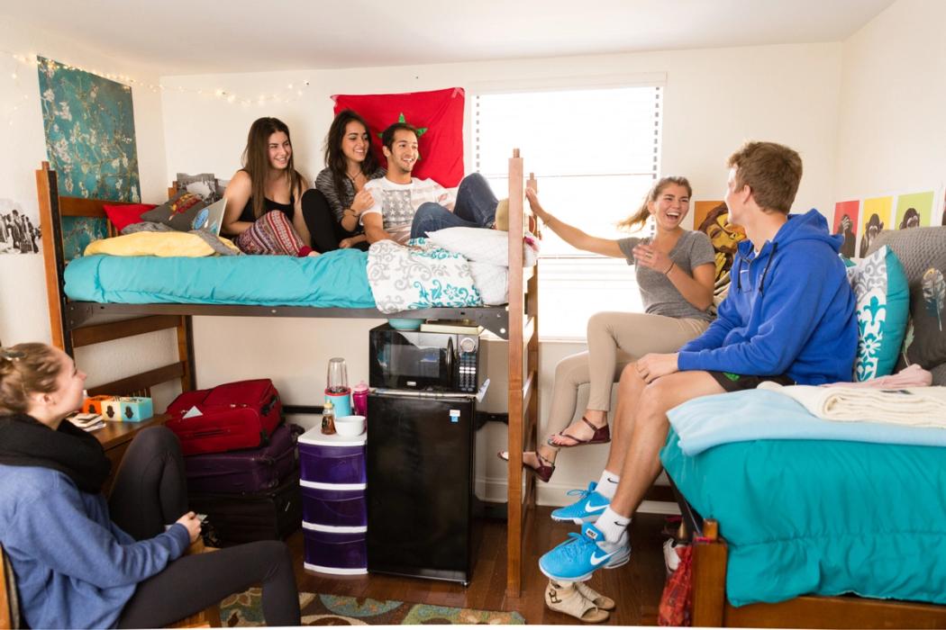 Students are talking and laughing in a dorm room