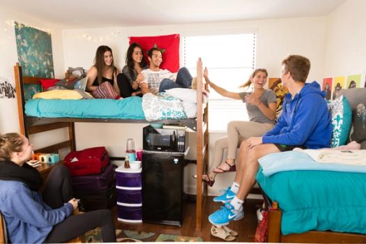 A group of students hang out in a dorm room.